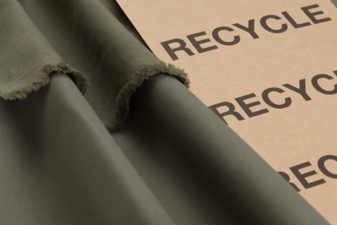 Recycled eco-friendly fabric with visible frayed edges placed beside a “RECYCLE” sign.