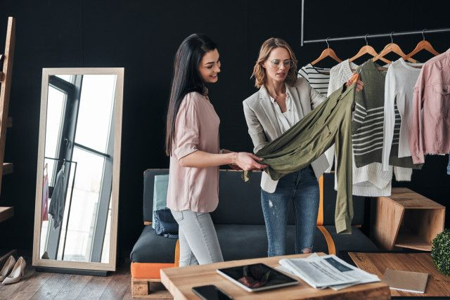 Fashion brand manager analyzing clothing designs with a colleague, building brand identity and ensuring market relevance.