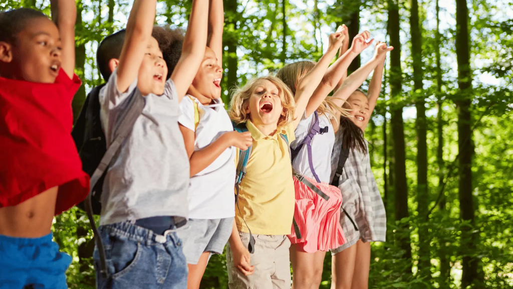 Excited group of kids cheering together outdoors, representing the fun, creativity, and confidence fashion design can bring to children.