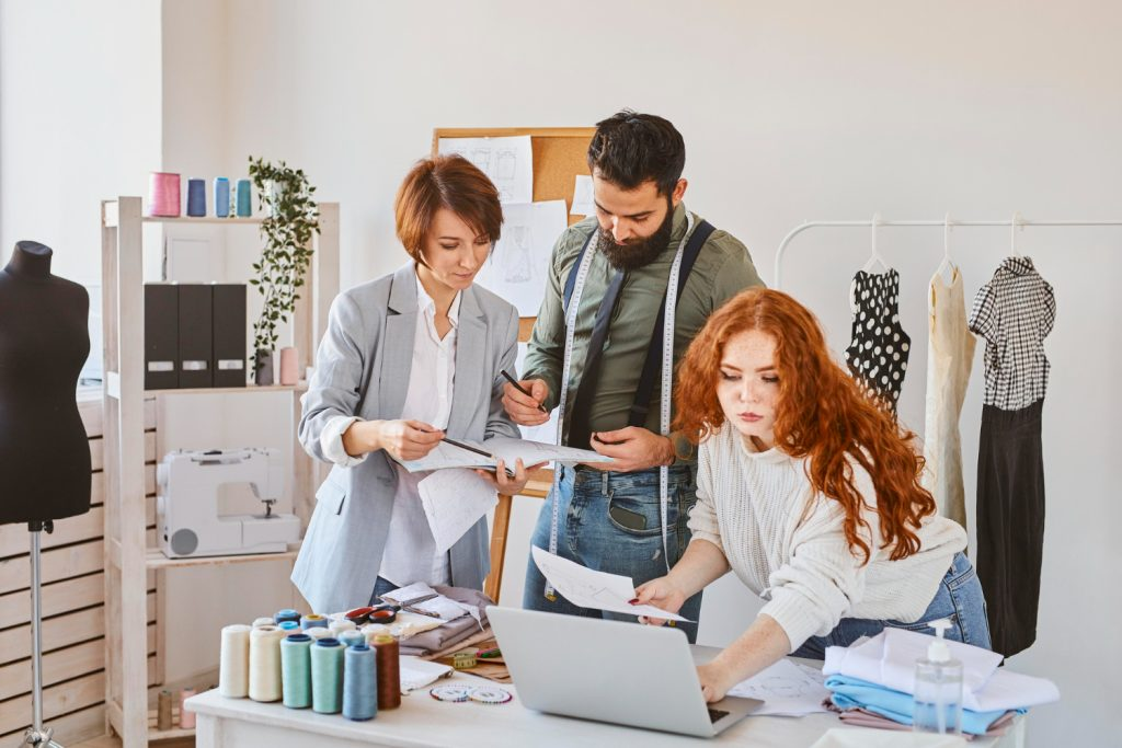 Creative director team reviewing fashion sketches and designs in a studio, guiding brand vision and high-level creative direction.